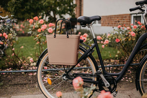 Tall Hinza bag made from recycled plastic in nougat colour with bicycle hooks, shown mounted on a bike