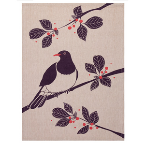 tea towel with a design featuring a New Zealand native bird called a kereru or wood pigeon. The bird is depicted in various shades of green and has a distinctive white and iridescent green patch on its neck. The background of the tea towel is a light beige color, and there are leaves and branches around the bird design. 100% cotton